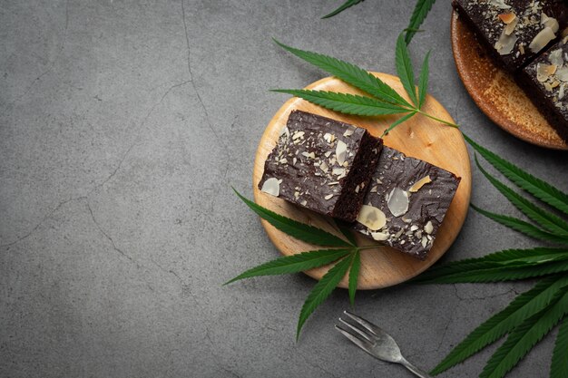 Cannabis Brownies und Cannabisblätter auf Holzschneidebrett gelegt