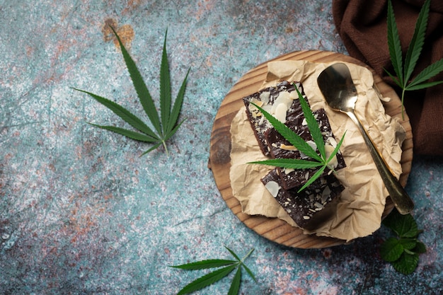 Cannabis Brownies und Cannabisblätter auf Holzschneidebrett gelegt