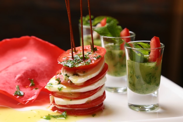 Kostenloses Foto caprese-salatspieße mit tomatenmozzarella und basilikum auf einem weißen quadratischen teller