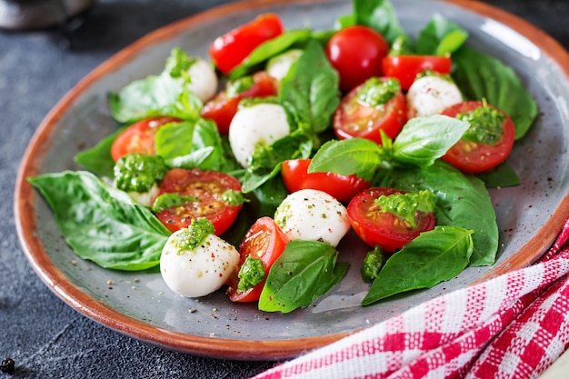 Capresesalat. Gesunde Mahlzeit mit Kirschtomaten, Mozzarellabällchen und Basilikum. Hausgemachtes, leckeres Essen. Konzept für eine schmackhafte und gesunde vegetarische Mahlzeit.