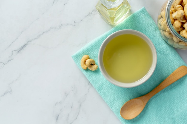 Cashewnussöl mit Cashewnüssen auf Marmorhintergrund