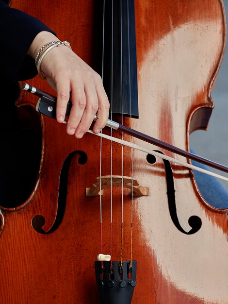 Cellist Spieler Hände. Violoncellist, der Cello auf Hintergrund des Feldes spielt. Musikalische Kunst, Konzept Leidenschaft in der Musik. Professioneller Cellospieler der klassischen Musik solo durchführen