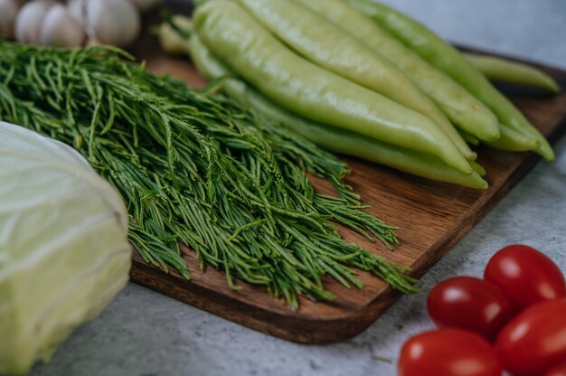 Cha-om, Paprika und Knoblauch auf einem Holzschneidebrett.