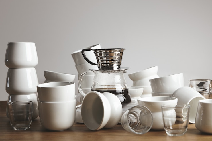 Kostenlose Foto chaos leere weiße und transparente kaffeetassen auf dickem holztisch. filterkaffeemaschine mit gefiltertem getränk in der mitte.