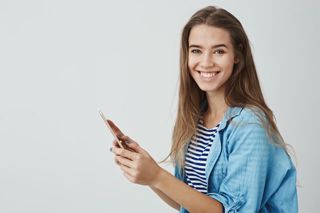 Charmante glückliche lächelnde Frau, die digitales Tablett hält, das nagelneues Gerät genießt