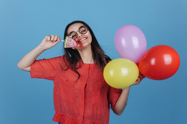 Charmante junge Brünette Frau steht mit einem Lutscher und Ballons