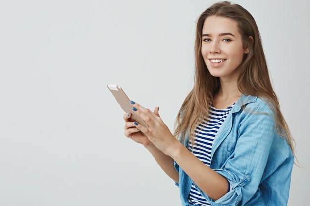 charmante weibliche moderne junge junge 25er europäische Frau langes gesundes Haar, das digitale Tablette hält sorglos entzücktes Lächeln