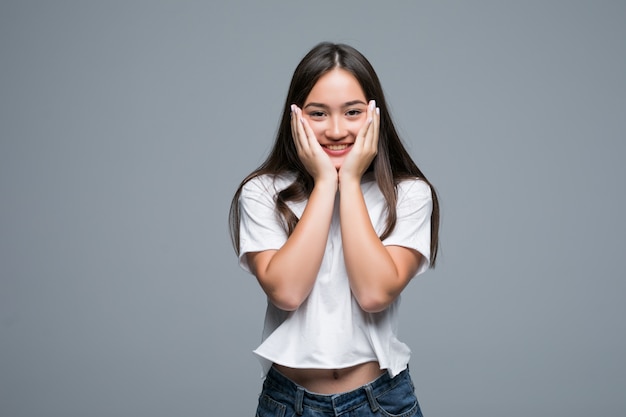 Charming der asiatischen Frau, die über grauem Hintergrund aufwirft und wegschaut