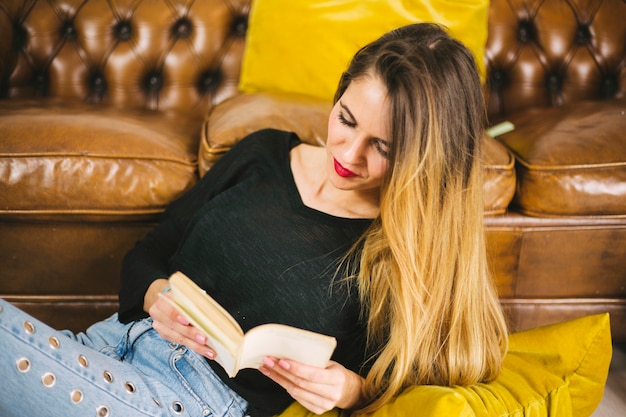 Kostenloses Foto charming woman lesen in der nähe von sofa