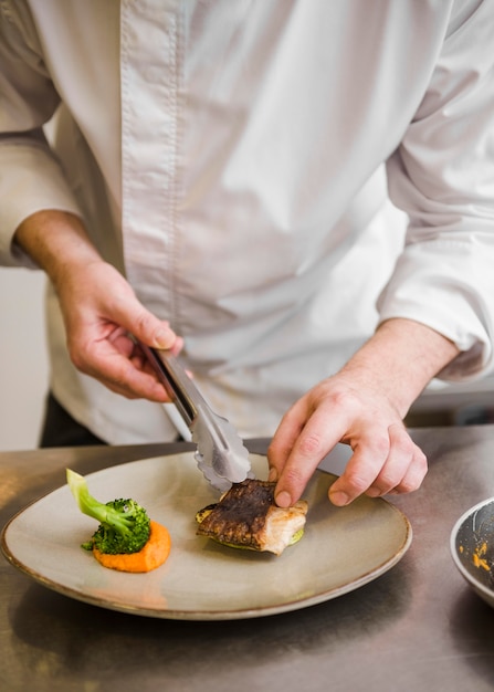 Chef, der gebratene Fischvoransicht vorbereitet