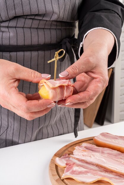 Chef, der Speck auf Obst einwickelt