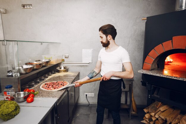 Chef in der Küche bereitet Pizza zu