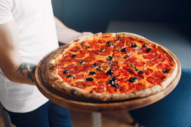 Chef in der Küche bereitet Pizza zu