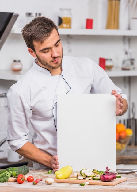 Kostenloses Foto chef in der küche, die papierschablone zeigt