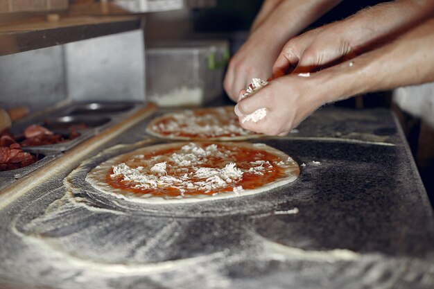 Chef in einer weißen Uniform bereiten eine Pizza zu