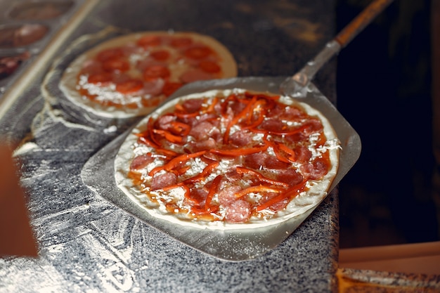 Chef in einer weißen Uniform bereiten eine Pizza zu