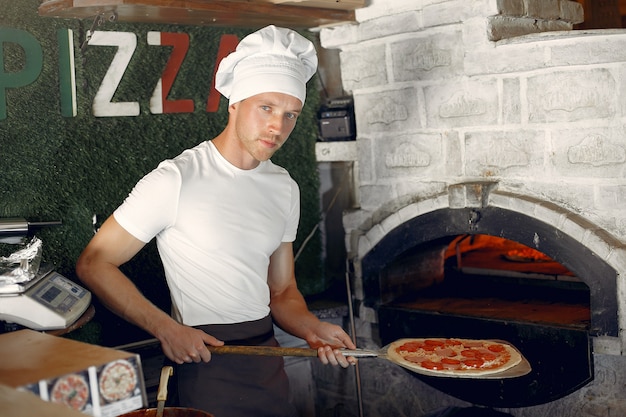 Chef in einer weißen Uniform bereiten eine Pizza zu