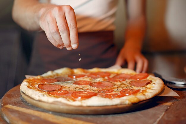 Chef in einer weißen Uniform bereiten eine Pizza zu