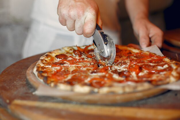 Chef in einer weißen Uniform bereiten eine Pizza zu