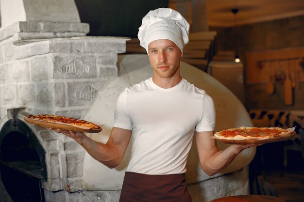 Chef in einer weißen Uniform bereiten eine Pizza zu