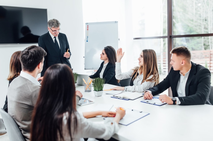 Kostenlose Foto chefgeschäftsmann, der papierhände hält und lächelt. junges team von mitarbeitern, die großartige geschäftsdiskussion im modernen coworking-büro machen.
