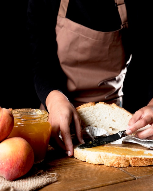 Chefkoch, der Pfirsichmarmelade auf Brot verteilt