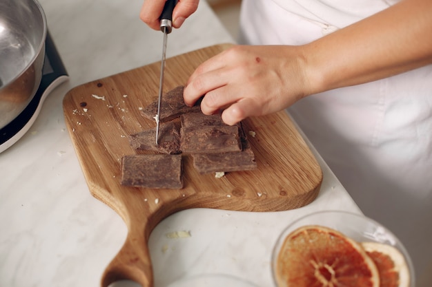 Chefkoch in weißer Kleidung bereitet einen Schokoladenkuchen zu. Dame bereitet Dessert vor. Frau backt einen Kuchen.