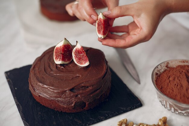 Chefkoch in weißer Kleidung bereitet einen Schokoladenkuchen zu. Dame bereitet Dessert vor. Frau backt einen Kuchen.