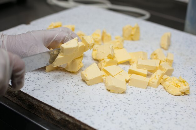 Chefkoch schneidet ungesalzene Butter in Stücke.