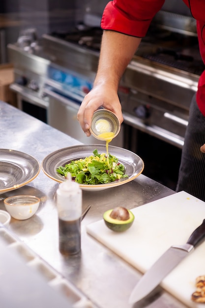 Chefkoch würzt köstlichen Salat in seiner Restaurantküche