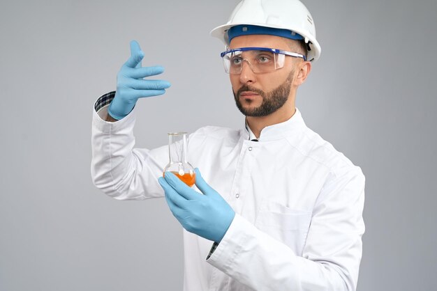 Chemiker, der Kolben mit orangefarbener Flüssigkeit hält
