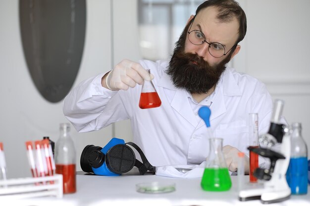 Chemiker verrückt. ein verrückter wissenschaftler führt experimente in einem wissenschaftlichen labor durch. führt forschungen mit einem mikroskop durch.