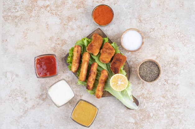 Chicken Nuggets und Bratwürste auf einem grünen Salatblatt auf einem Holzbrett.