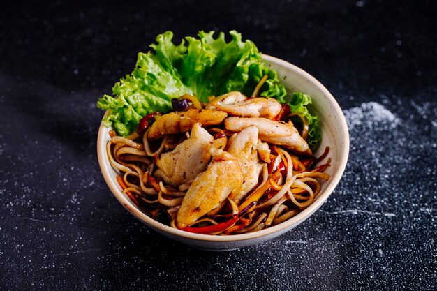 Chinesische Nudeln in Schüssel mit Filet und Salat.