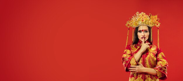 Chinesische traditionelle anmutige Frau im Studio über Rot.