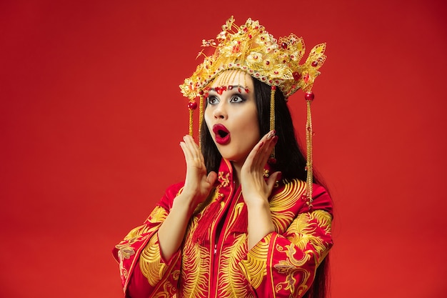 Chinesische traditionelle anmutige Frau im Studio über roter Wand