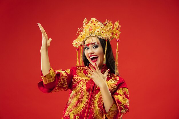 Chinesische traditionelle anmutige Frau im Studio über roter Wand