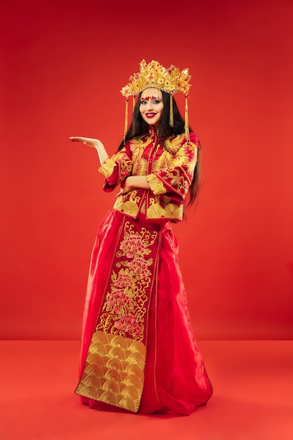 Chinesische traditionelle anmutige Frau im Studio über roter Wand