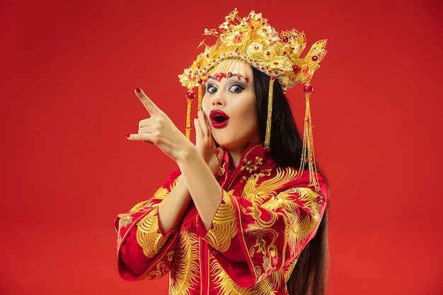 Chinesische traditionelle anmutige Frau im Studio über roter Wand