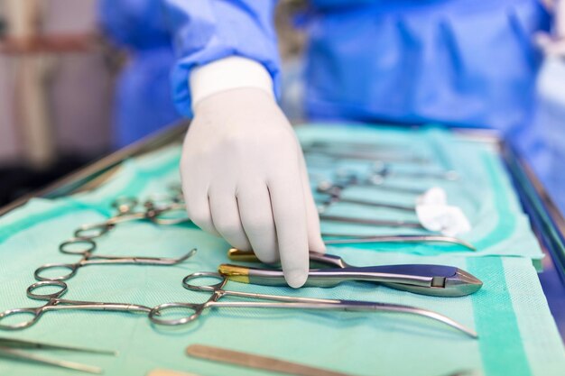 Chirurg nimmt chirurgisches Werkzeug aus dem Tablett auf Chirurg bereitet sich auf die Operation im Operationssaal vor Er ist in einem Krankenhaus