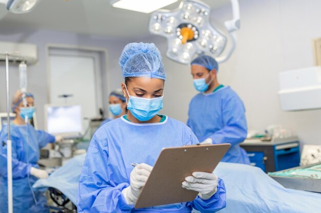 Chirurg schreibt auf Zwischenablage im Operationssaal Anästhesist schreibt die Updates
