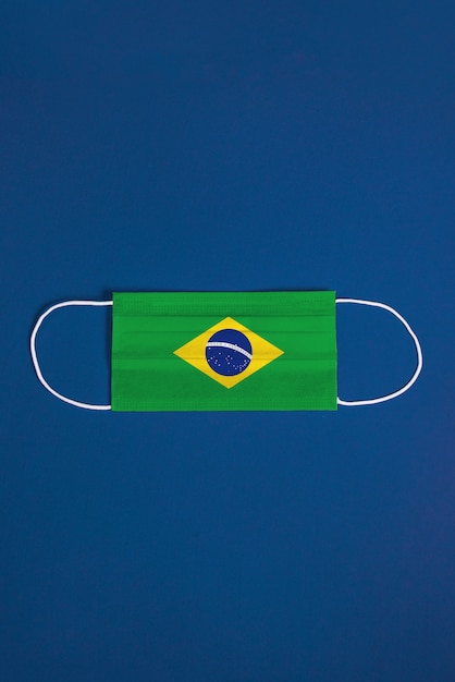 Chirurgische Maske auf blauem Hintergrund mit brasilianischer Flagge