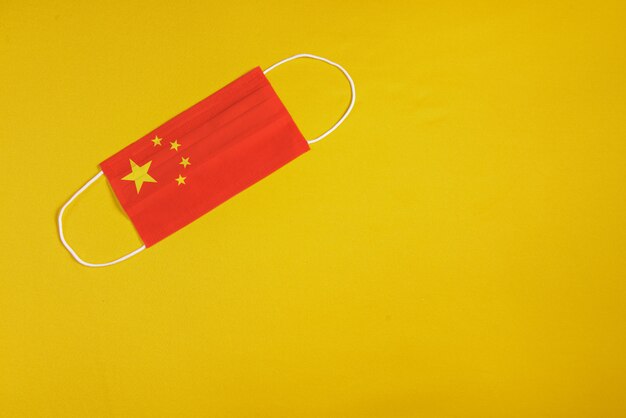 Chirurgische Maske auf gelbem Hintergrund mit Flagge von China