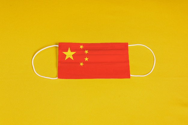 Chirurgische Maske auf gelbem Hintergrund mit Flagge von China