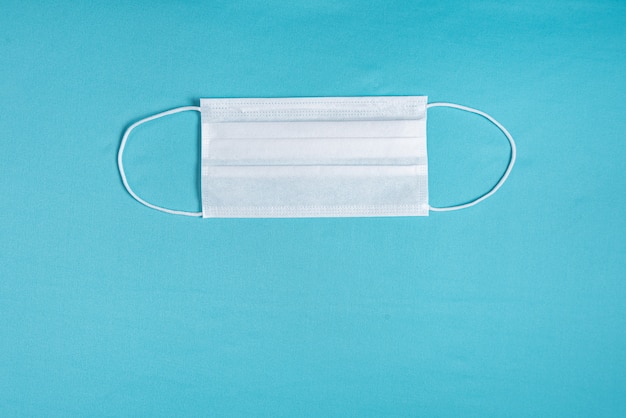 Chirurgische Maske über minimalistischem blauem Hintergrund