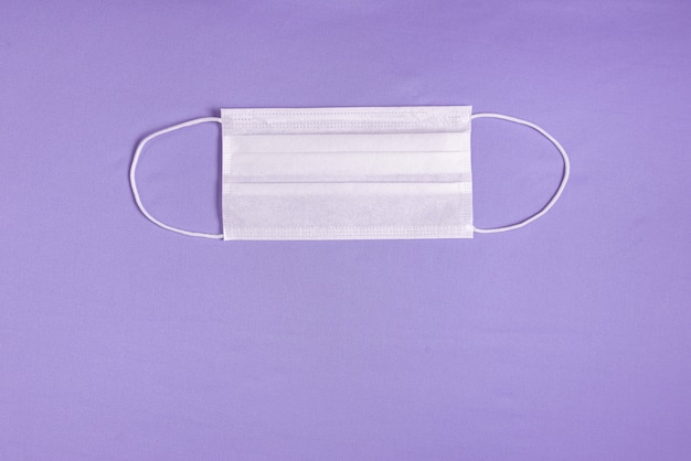 Chirurgische Maske über minimalistischem lila Hintergrund