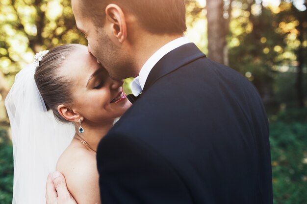 Close-up der Bräutigam seine Frau auf die Stirn küssen