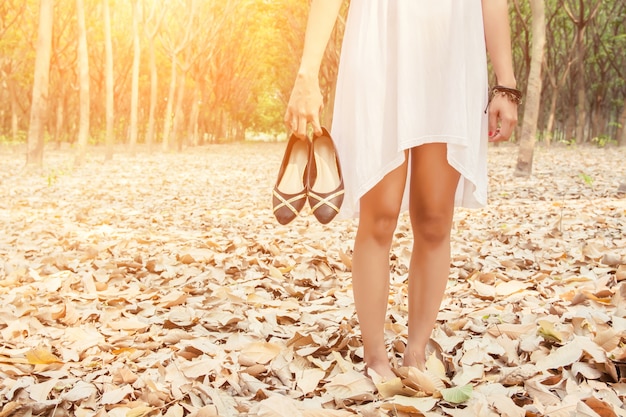 Close-up der Frau, die ihre Schuhe in der Hand trägt,