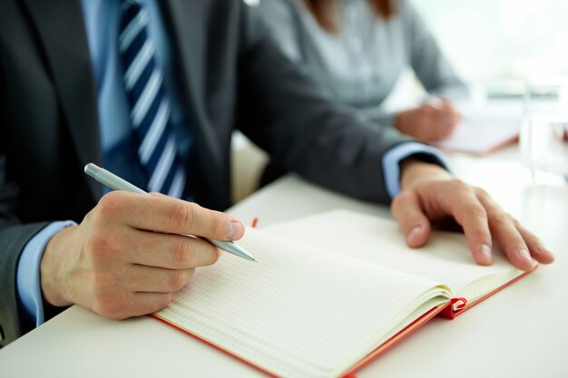 Close-up der Geschäftsmann mit einem Stift und einem offenen Notebook