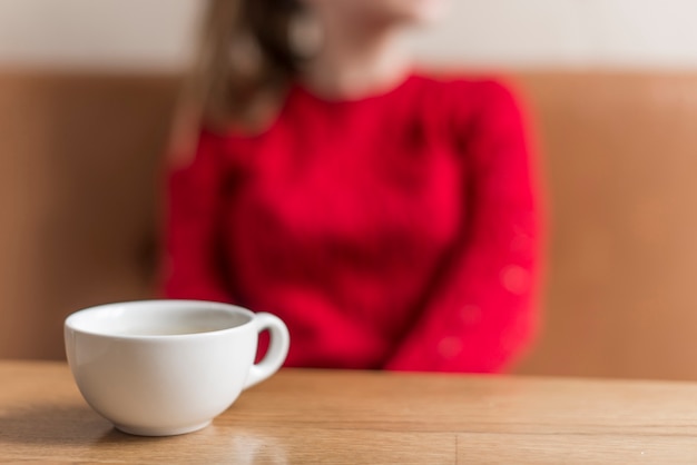 Close-up der weißen Tasse mit unscharfem Hintergrund Frau